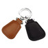 A rustic key ring featuring two leather tags, one in brown and the other in black, attached to a silver keyring.
