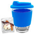 A reusable coffee cup with a blue silicone sleeve and lid, accompanied by a pack of jelly lollies.