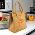 A brown paper cooler lunch bag with short handles and a logo. Surrounded by fresh produce on a kitchen counter.