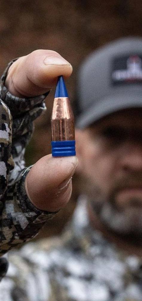 Powerbelt Bullets Man in snow camo holding bullet.