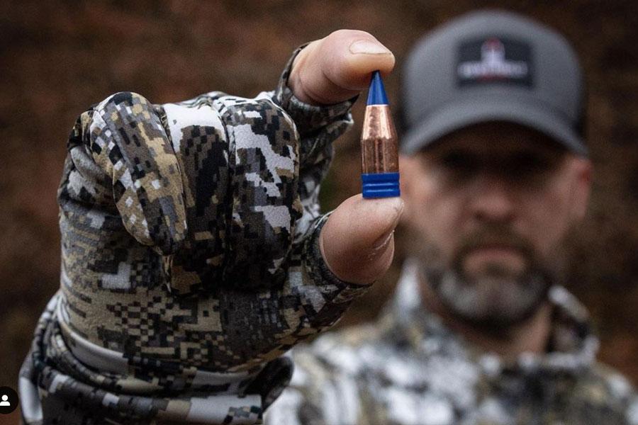 Powerbelt Bullets Man in snow camo holding bullet.