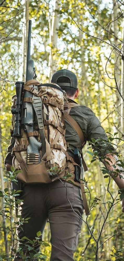 Quake gear in the field. Back of man walking through birch grove with Quake gear on.
