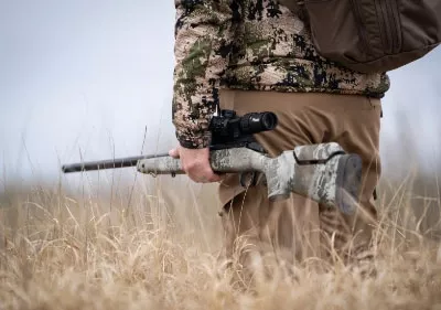 Man standing in field with gun.