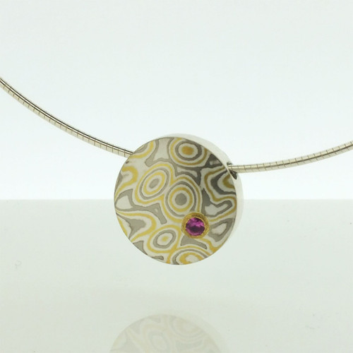 Mokume gane medium discus pendant  in 22k gold, 18k white gold and silver with a pink sapphire in a low 22k gold setting 
