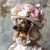 Dachshund in a hat featuring a variety of flowers, predominantly in shades of pi