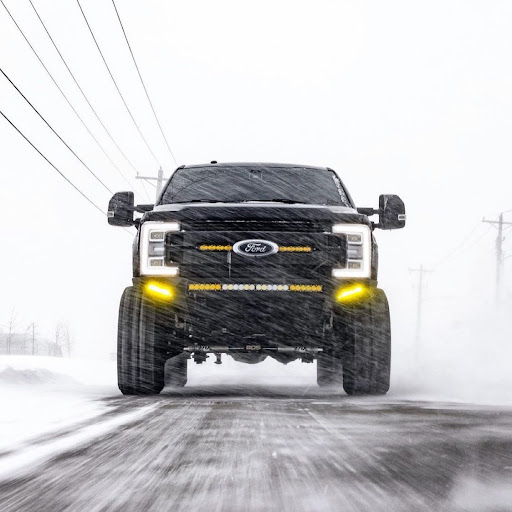 Ford Superduty with aftermarket lighting driving through a winter storm