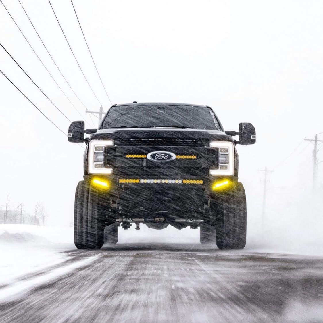 Ford off-road truck with aftermarket lighting driving in the snow