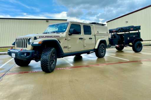 Sand Jeep Gladiator with aftermarket parts towing a small black trailer