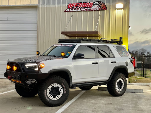 White Toyota 4-Runner with off-road modifications parked in front of Offroad Alliance showroom
