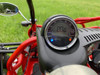 TrailMaster Go Kart 200E XRX Go Kart, digital speedometer display showing 0.0 MPH with indicator lights, red frame and control dashboard, outdoors on green grass.