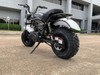 TrailMaster Hurricane 200X Mini Bike, shown in an outdoor parking lot with modern building background, featuring rugged tires, black frame, and silver accents.