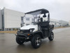 Trailmaster Taurus 200U Utility SXS UTV, black and white off-road electric utility vehicle with rugged tires, front bumper, and canopy, parked outdoors on concrete surface.
