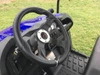 Trailmaster Taurus 200U Utility SXS UTV, interior dashboard and steering wheel with rugged floor mat, on grassy outdoor background.