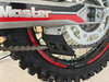 TrailMaster TM35X-250 Deluxe Dual-Sport Dirt Bike, close-up of the rear wheel, chain, and gear mechanism with detailed view of the tire tread and frame.