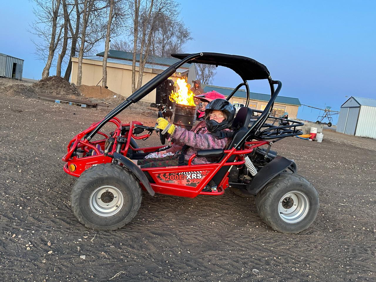TrailMaster 200 XRS EFI – Full-Size Adult Go Kart with Fuel Injection, CVT, 200cc Engine, featuring a red frame, rugged tires, and a canopy, driven by a child wearing a helmet in an outdoor dirt track setting.