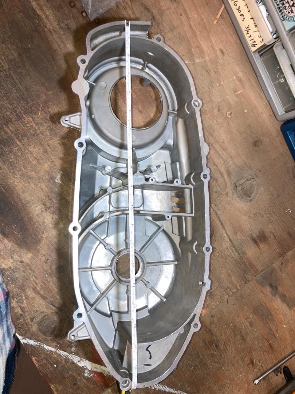 TrailMaster 300 EFI Model Go Kart CVT side cover, metallic silver engine casing with structural ribs and mounting holes on a wooden workbench.