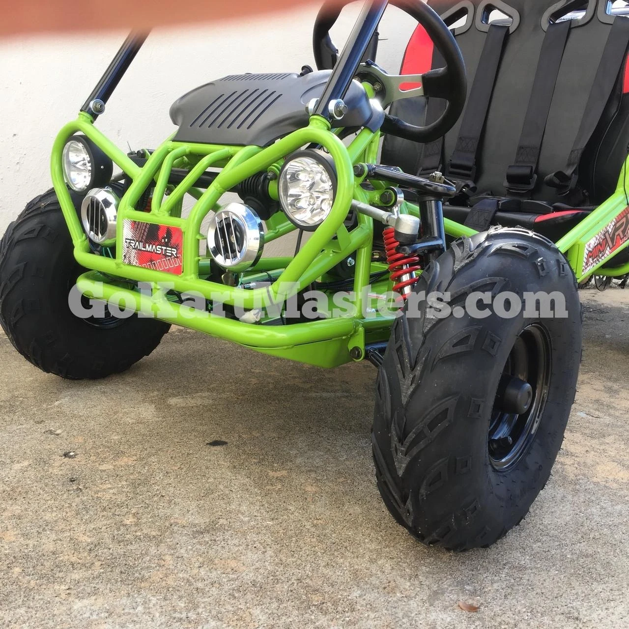 TrailMaster Mini XRX/R+ Go Kart with Reverse - assembled green and black off-road toy vehicle for children aged 4 and up, featuring large rugged tires, front LED lights, a black seat with safety harnesses, and a steering wheel for young drivers.