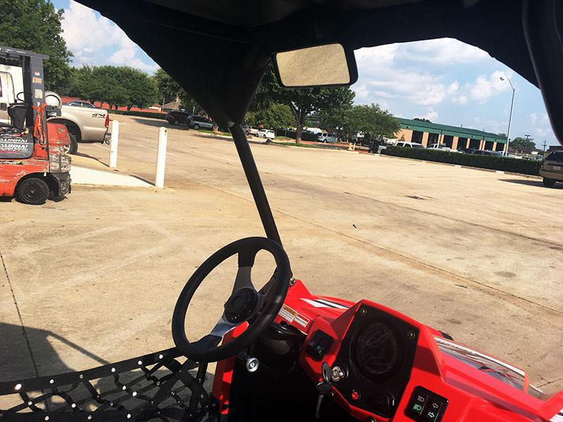Trailmaster Challenger 200 UTV Youth SXS Sport Carburetor, interior view of red UTV showing steering wheel, dashboard, and side mirror in outdoor parking lot.