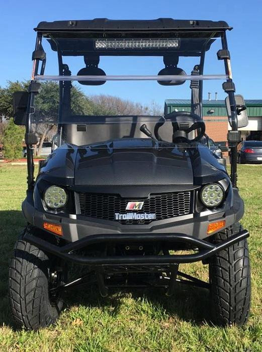 Trailmaster Taurus 200U Utility SXS UTV, black outdoor utility vehicle with sturdy frame, large tires, and front bumper, parked on grass under clear sky.
