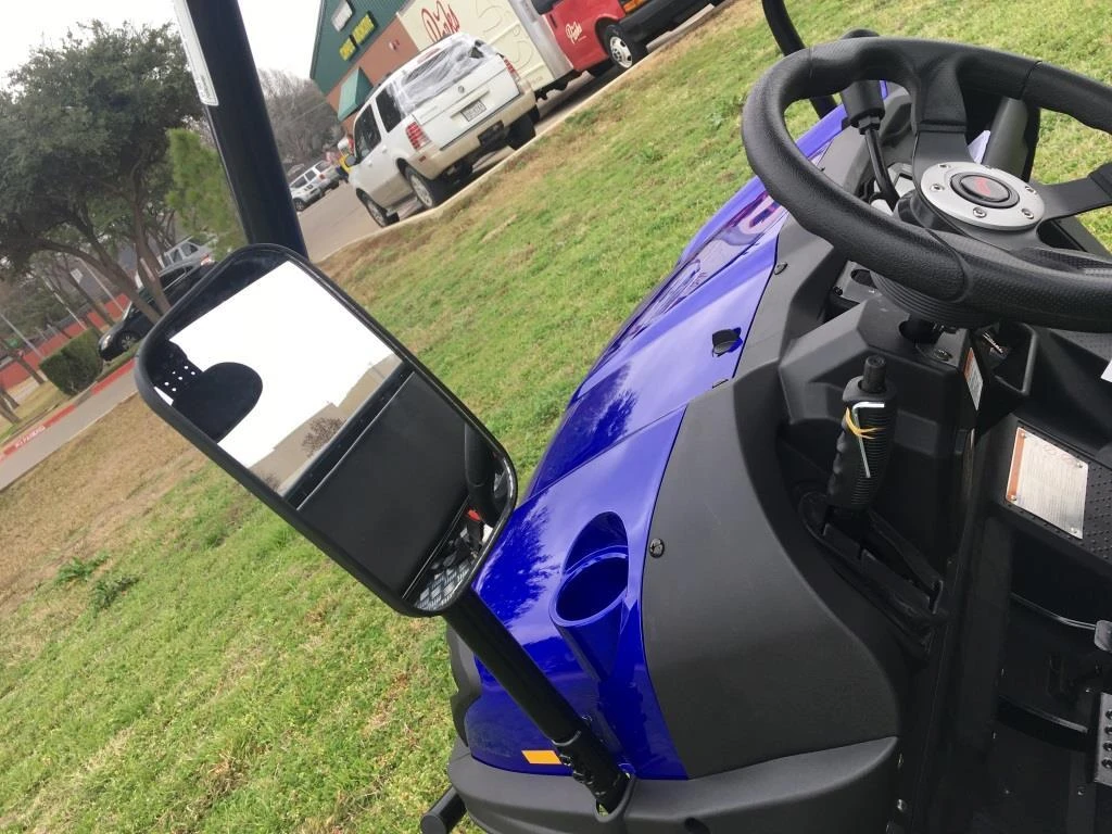 Trailmaster Taurus 200U Utility SXS UTV, close-up of the vehicle's interior and steering wheel with side mirror, outdoors on grass field.