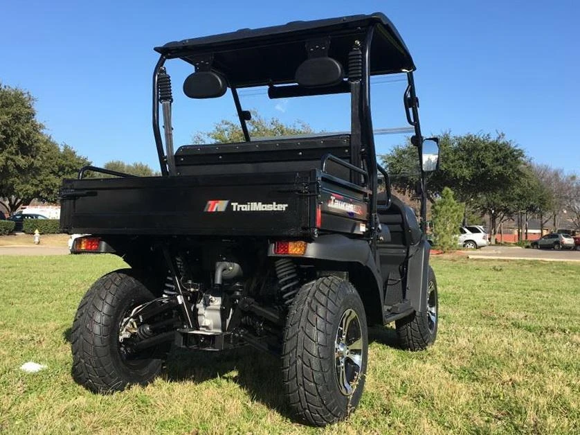 Trailmaster Taurus 200U Utility SXS UTV, black recreational off-road vehicle with large tires and open cargo bed on a grassy field.