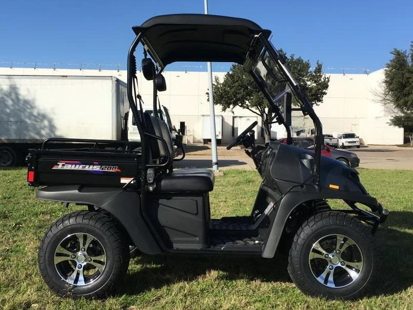 Trailmaster Taurus 200U Utility SXS UTV, black compact off-road vehicle with four wheels, black roof, and side mirrors, parked on grass in outdoor setting.