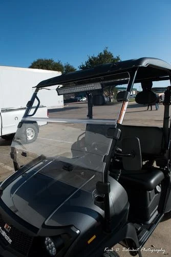 Trailmaster Taurus 200U Utility SXS UTV, front view of the black utility vehicle with a clear windshield and roof, parked outdoors under a clear blue sky.