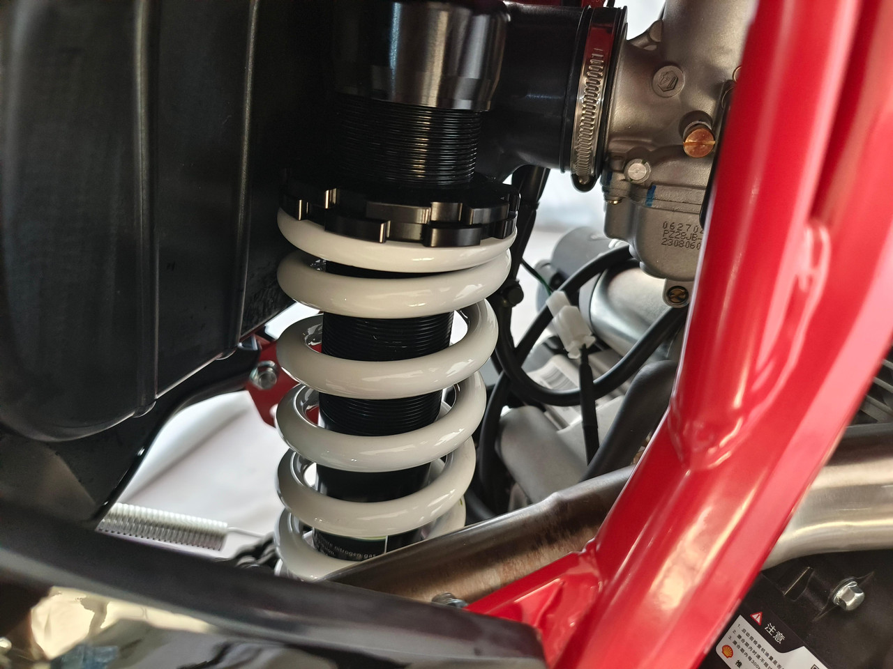 TrailMaster TM35X-250 Deluxe Dual-Sport Dirt Bike, close-up view of the motorcycle's suspension system with a white coil spring and black components.
