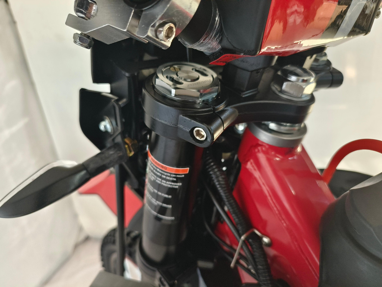 TrailMaster TM35X-250 Deluxe Dual-Sport Dirt Bike, close-up of the front suspension and handlebar area showing detailed parts and black and red color scheme.