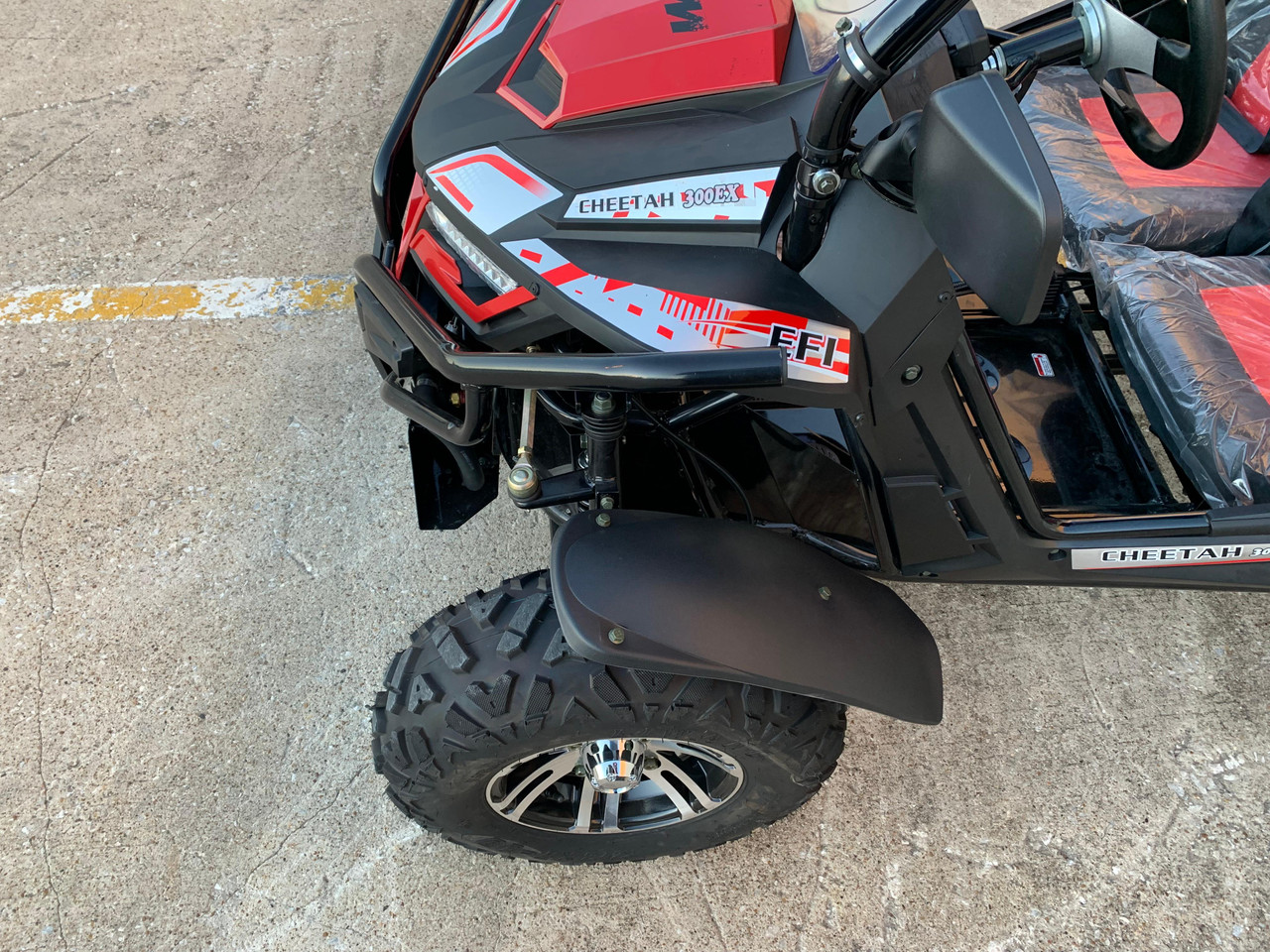 TrailMaster Cheetah 300EX Deluxe EFI Go-Kart/UTV Crossover, close-up of the front wheel and part of the black and red vehicle body with decals.