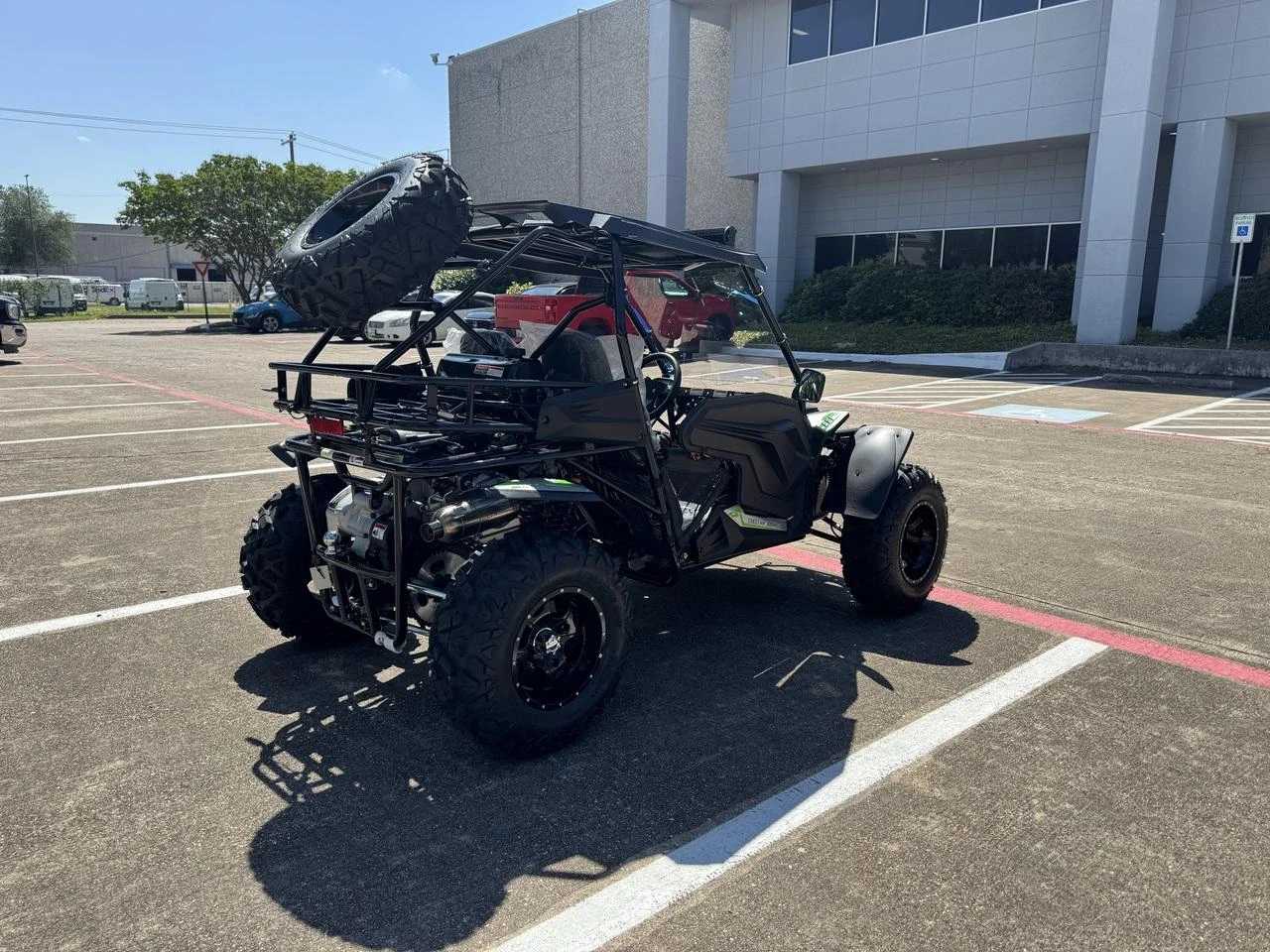 TrailMaster Cheetah 300Pro Premium EFI Go-Kart/UTV Crossover, rugged off-road vehicle with large tires, lightweight frame, and exhaust system, parked in lot outside building.