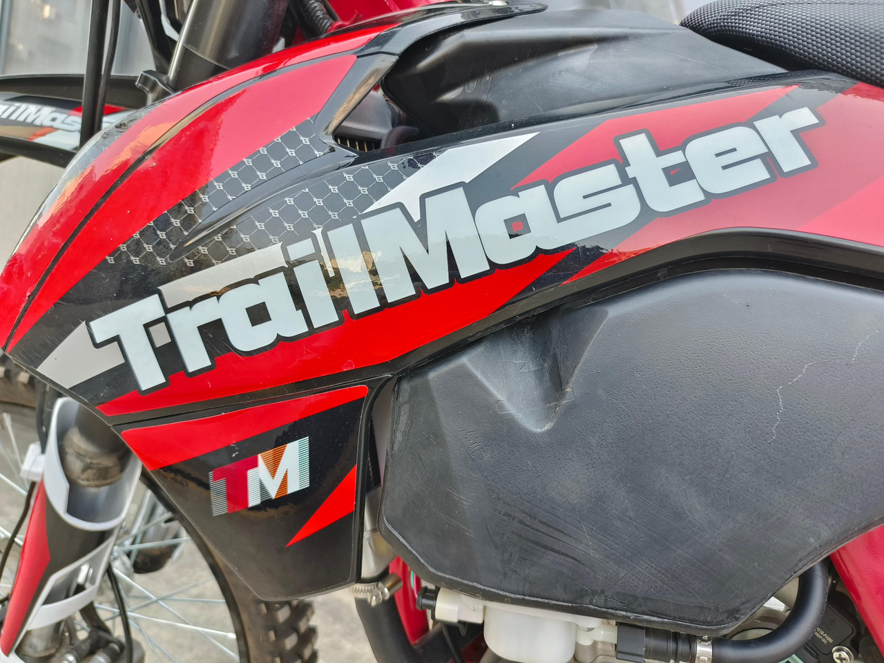 TrailMaster TM38EX (300 EFI) Deluxe Dual-Sport Dirt Bike, close-up of the black and red bodywork with the brand name prominently displayed.