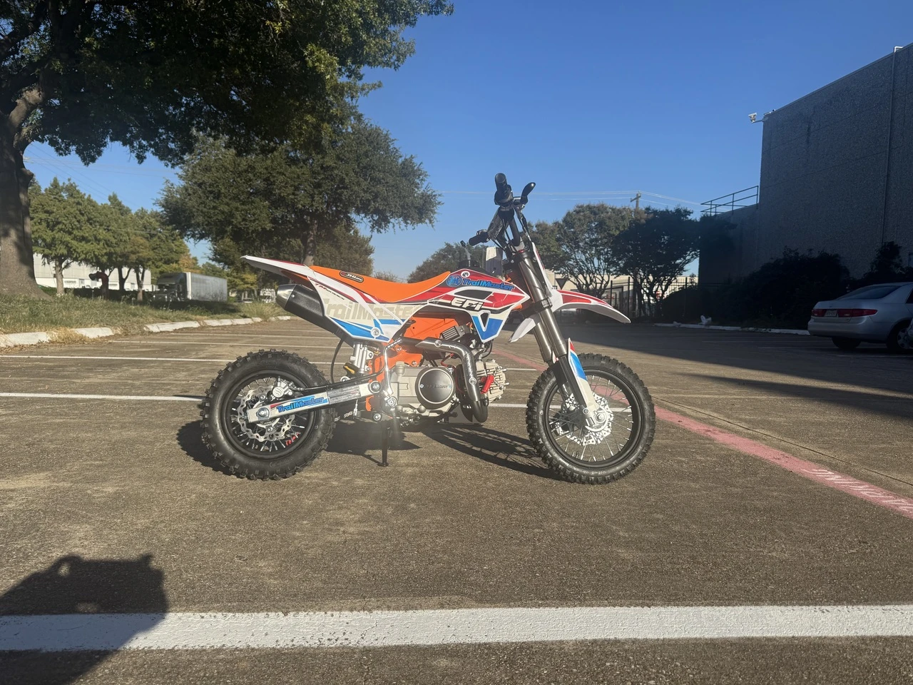 Right side of the red TrailMaster SK110ES kids dirt bike showing the exhaust and kick starter.
