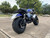 TM Hurricane 200X PRO Mini Bike with Electric Start, black and blue design, rugged tires, and detailed suspension, parked on an outdoor surface.