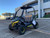 TM Cheetah i6 Battery powered vehicle, black and yellow off-road electric utility vehicle with two seats and a roof, parked outdoors in a parking lot.