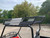TM Challenger 200 EGX Golf Cart Style UTV, off-road utility vehicle with a metal roof rack and black frame, parked on a concrete lot with trees in the background.
