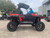 TM 4x4 SportsCross 1000 Side by Side, a rugged off-road vehicle with large tires, black and red body, and a protective roof in a parking lot.