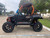 TM 4x4 SportsCross 1000 Side by Side, black and orange off-road utility vehicle with large rugged tires, open cabin, and roll cage, parked outdoors.