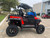 TM 4x4 SportsCross 1000 Side by Side, off-road utility vehicle with four large tires, red and black body, and a canopy roof in a parking lot.