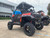 TM 4x4 SportsCross 1000 Side by Side, rugged off-road utility vehicle with large tires, red and black body, and open cabin design parked in an outdoor lot.