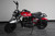 TM Hurricane 200X Mini Bike, red and black mini motorcycle with a seat covered in plastic and large off-road tires.