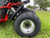 TM 200 XRX EFI PREMIUM Go Kart, close-up of the large off-road tire and part of the chassis in a grassy field.