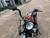 TM Hurricane 200X Upgraded Mini Bike, front view showing large headlight, handlebars, and seat in an outdoor parking lot.