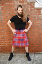 Man in MacFarlane bespoke kilt in red and purple tartan by brick wall