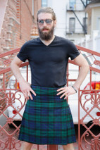 Man in MacKay green and navy tartan kilt with dark T-shirt by a red railing