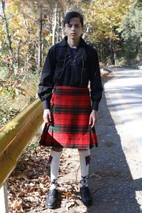 Teen boy in Maxwell tartan kilt with black jacobite shirt on a woodland road