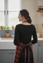 Back view of woman in kitchen wearing red and green tartan apron tied at waist