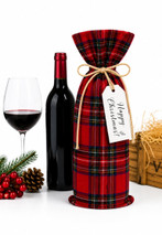 Tartan wine gift bag in red plaid with twine tie beside a wine bottle and glass