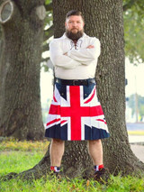 Man in Union Jack patriotic kilt and white shirt standing by a tree