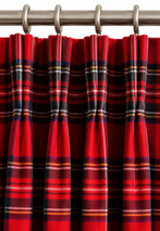 Close-up of red tartan pinch pleat curtain heading on metal rings